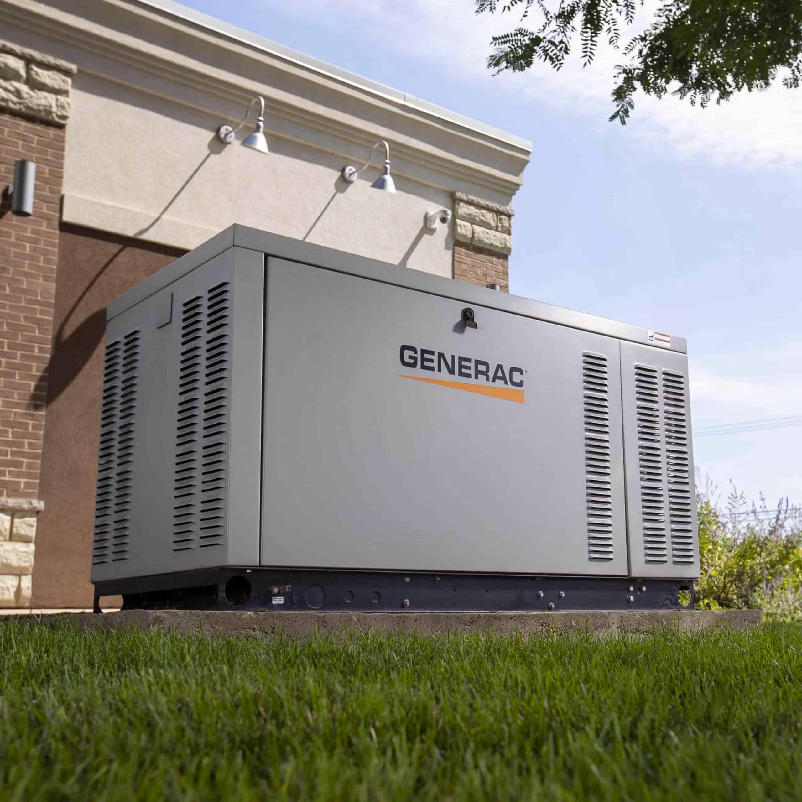 Large Generac generator on a concrete pad beside a building, surrounded by grass, with trees partially visible above.