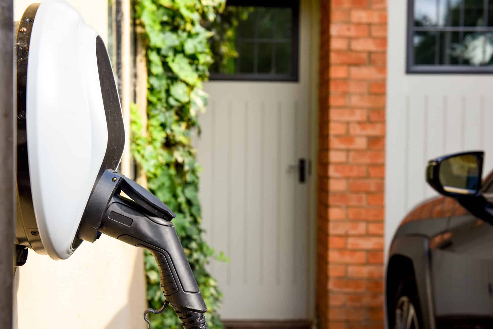 Premium EV Outlet plugged into the wall of a house to charge an electric car.