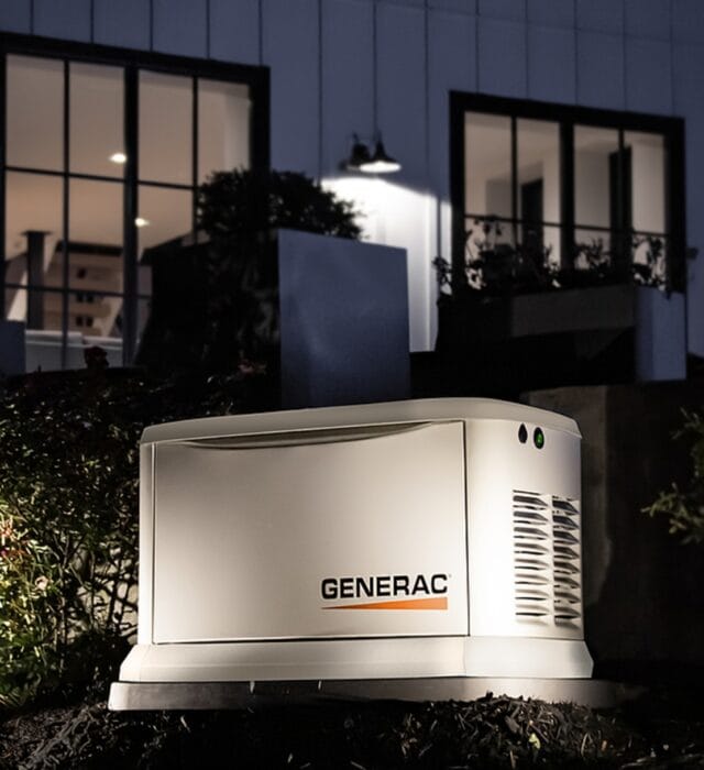 Home standby generator illuminated by outdoor lighting at night.