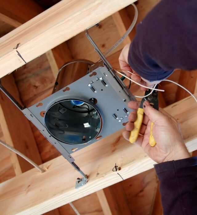Electrician installing can lighting during new home construction.